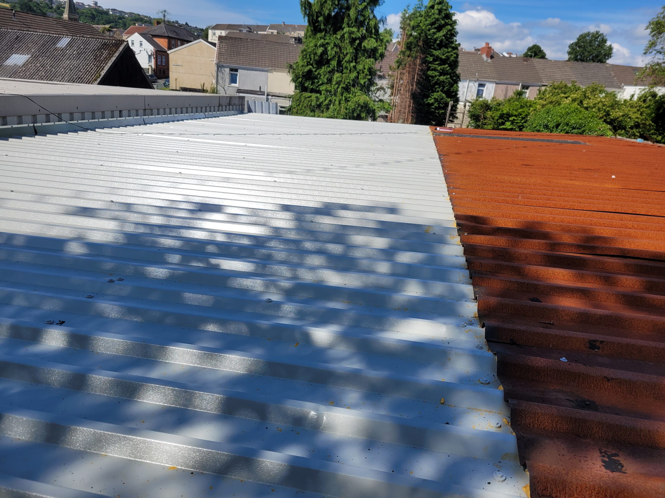 Side-by-side view of the new metal roof and the old rusted roof on a garage.