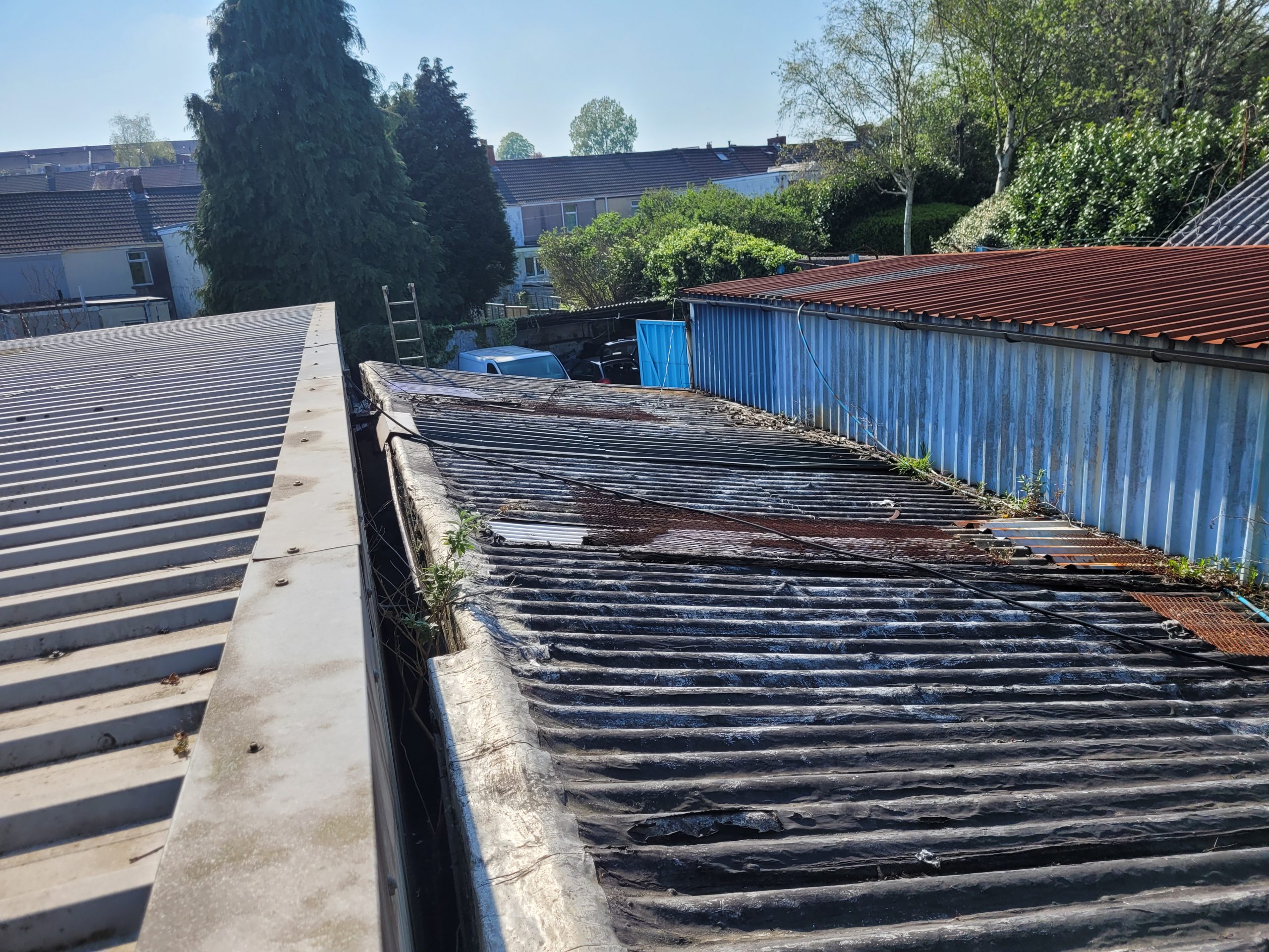 Old and damaged roof with vegetation and rust, showing the condition of the garage before renovation.