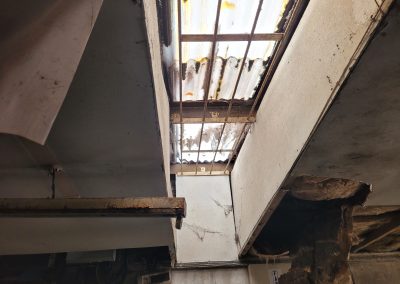 "Interior view of the damaged garage with broken roof panels and exposed beams.